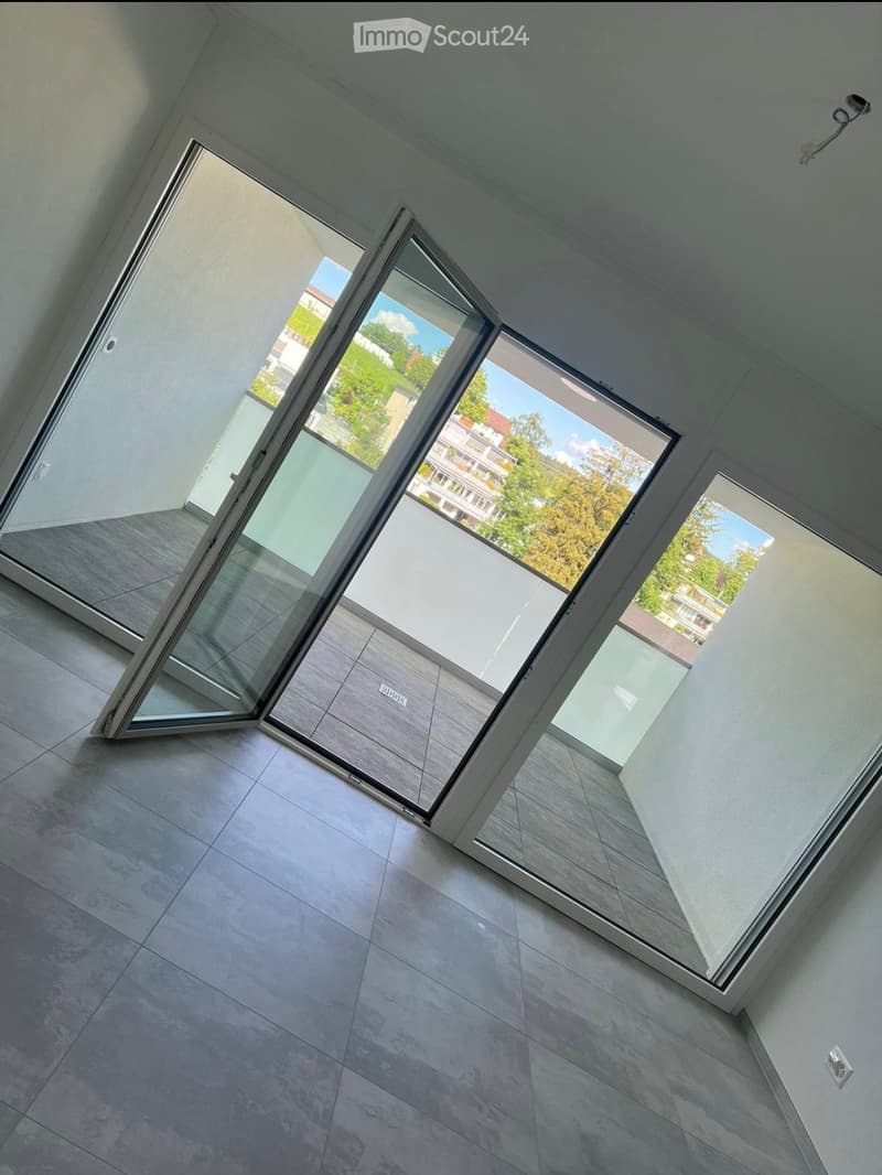 Empty room with large sliding glass doors leading to a balcony, tiled floor, and white walls.