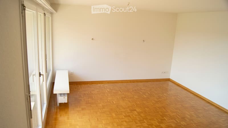 Empty room with wooden flooring, white walls, and large windows. No furniture or equipment present.