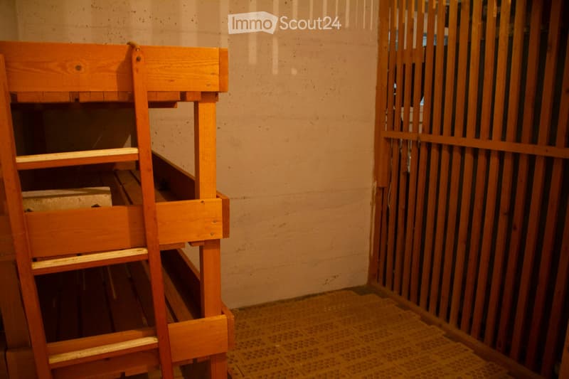 Empty room with wooden ladder and wooden barrier, bare walls, and tiled floor.