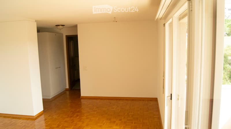 Empty hallway with wooden flooring, white walls, and a closed door leading to another room.
