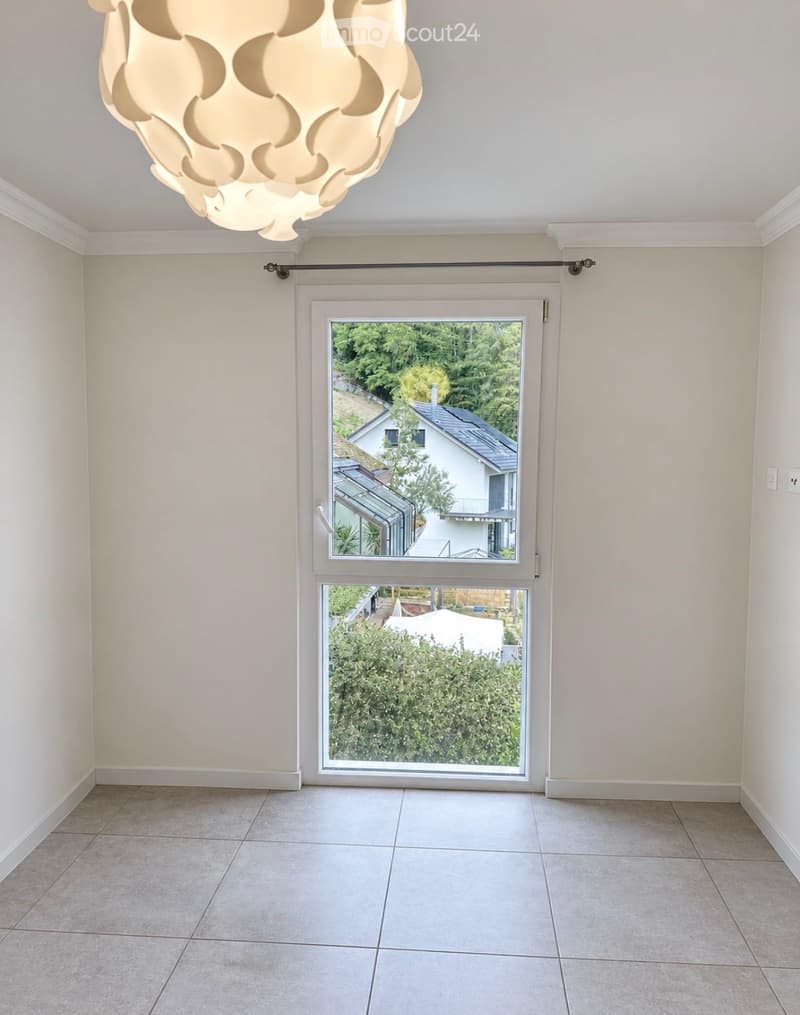 Empty room with tiled floor, white walls, large window with blinds, and a modern light fixture on the ceiling.