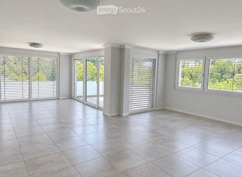 Empty room with tiled floor, large windows with blinds, and a sliding glass door leading to an outdoor area.