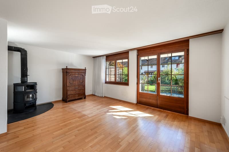 Spacious room with wooden flooring, a wooden cabinet, a wood-burning stove, large wooden sliding doors, and a wooden window with a curtain.