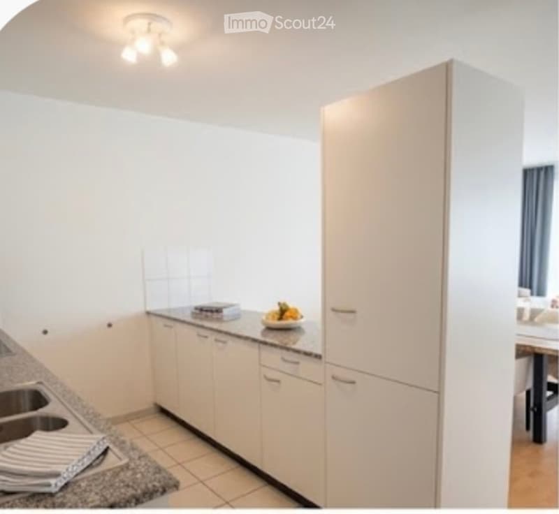 Modern kitchen with white cabinets, granite countertop, sink, and a bowl of fruit on the counter.