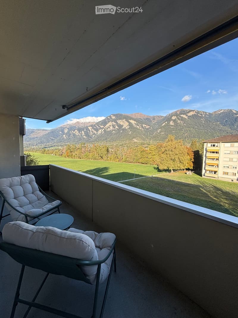 Balcony with a scenic mountain view, featuring two chairs and a small table.
