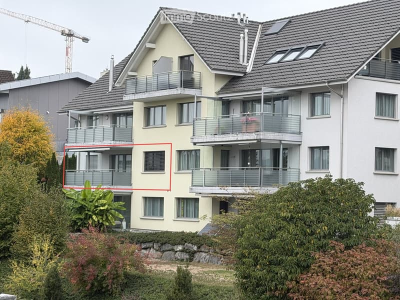 Modern multi-story residential building with multiple balconies, large windows, and a well-maintained garden area.