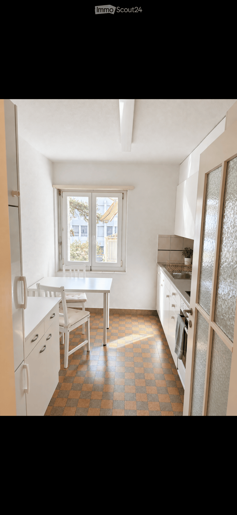 Modern kitchen with white cabinets, a dining area, and a window overlooking a balcony.