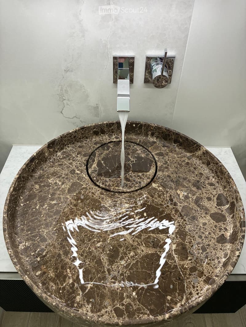 Modern bathroom sink with a sleek, marble-like finish and a contemporary faucet design.