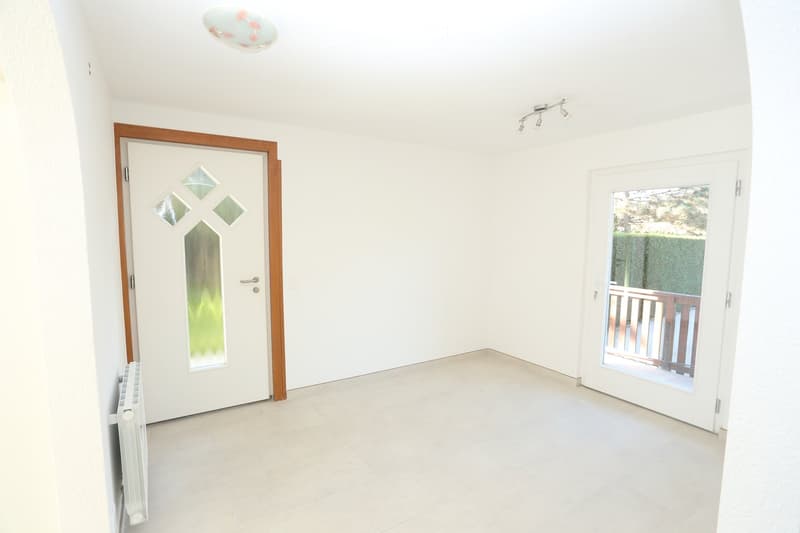 Empty room with white walls, tiled floor, and two doors: one leading outside and another interior door.