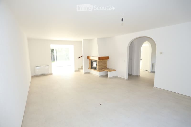 Empty room with white walls, tiled floor, fireplace, and arched doorway.