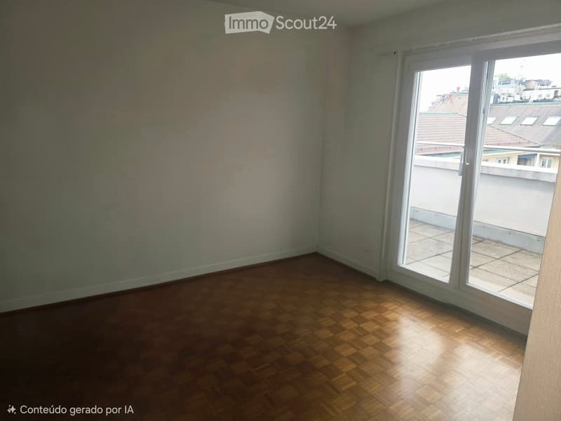 Empty room with wooden flooring and large window offering a view of rooftops. Walls are partially painted.