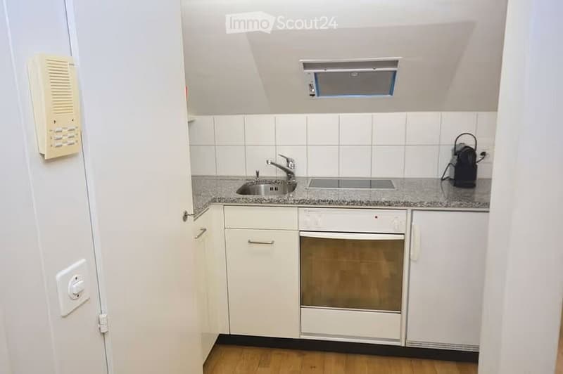 Modern kitchen with white cabinets, granite countertop, stainless steel sink and faucet, built-in oven, and wooden flooring.