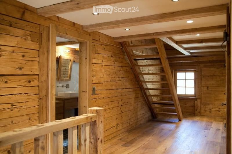 Cozy wooden bathroom with exposed beams, a staircase leading to another level, and a sink with a mirror.