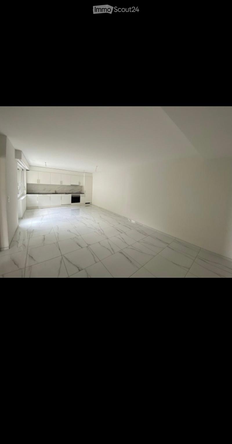 Empty kitchen with white cabinets, tiled floor, and basic appliances like a sink and oven, but no furniture or personal items.