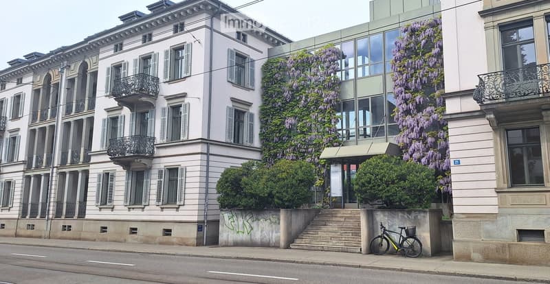 Multi-story residential building with classical architecture, large windows, balconies, and climbing wisteria vines.