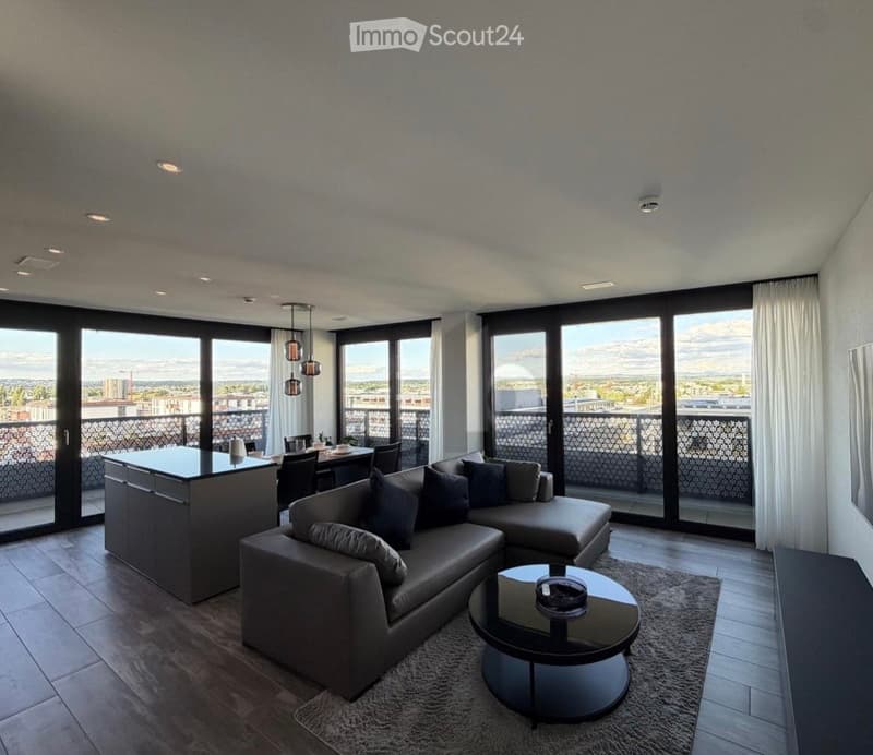 Modern living and dining area with large windows offering a city view, featuring a grey sectional sofa, coffee table, dining table with chairs, and a kitchen island.
