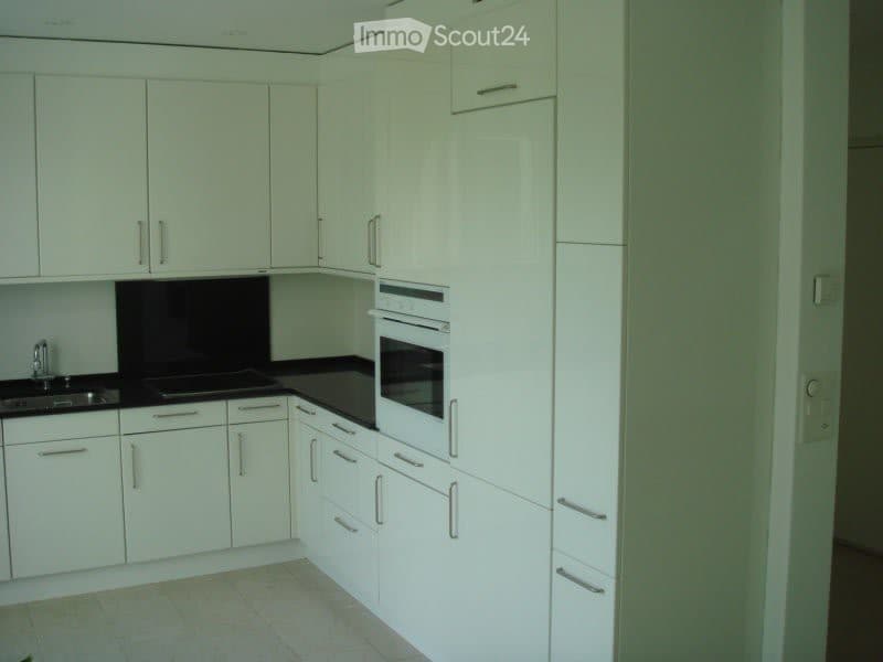 Modern kitchen with white cabinets, black countertops, and stainless steel sink and faucet.
