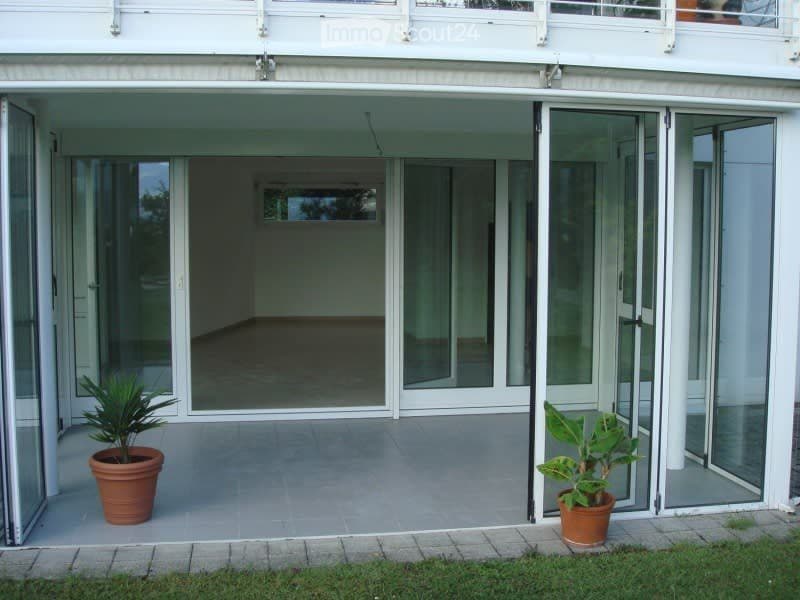 Balcony with large glass sliding doors, tiled floor, and two potted plants on either side.