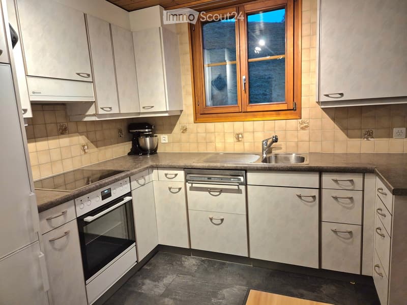 Modern kitchen with white cabinets, stainless steel appliances, granite countertops, and a window with wooden frame.