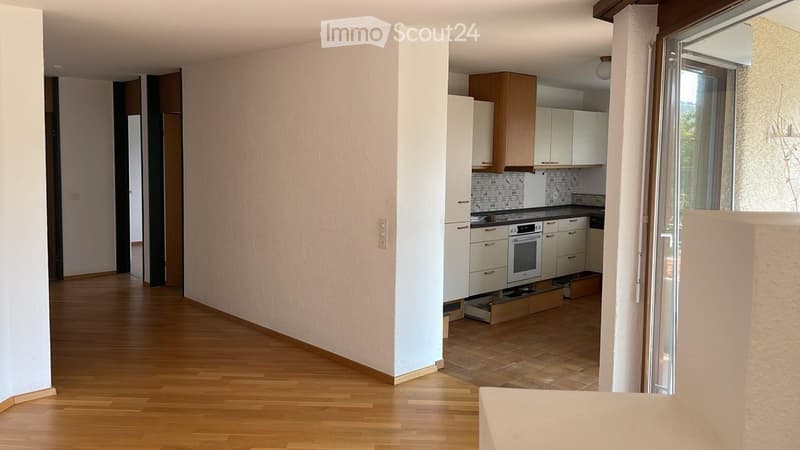 Modern kitchen with light-colored cabinets, an oven, and a tiled backsplash. The space features wooden flooring and large windows letting in natural light.