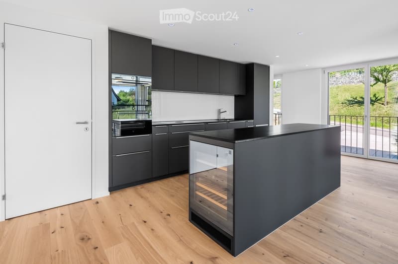 Modern kitchen with dark grey cabinets, a central island with a wine rack, and a sleek black countertop.