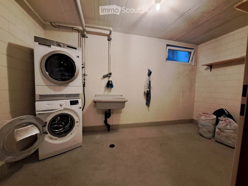 Utility room with a washing machine, dishwasher, and sink, featuring exposed brick walls and a small window.