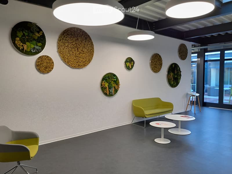 Modern, minimalist room with a green sofa, a yellow chair, white tables, and decorative wall art.