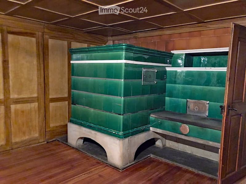 interior of room, wooden wall panels, green tiled furnace with wooden bench, wooden floor