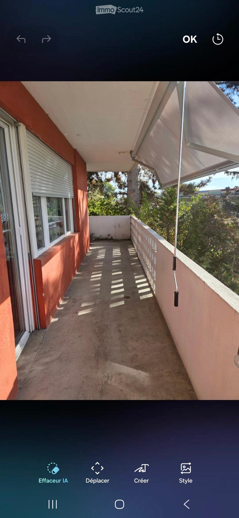 Balcony with beige carpet, white railing, and retractable awning, overlooking greenery.
