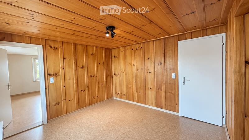 Empty room with wooden walls and ceiling, tiled floor, and white doors.