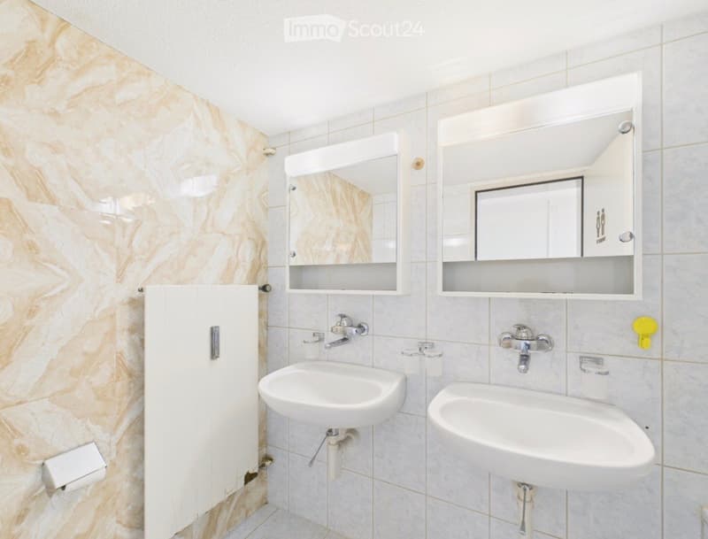 Modern bathroom with two sinks, mirrored cabinets, and marble-style tiles.