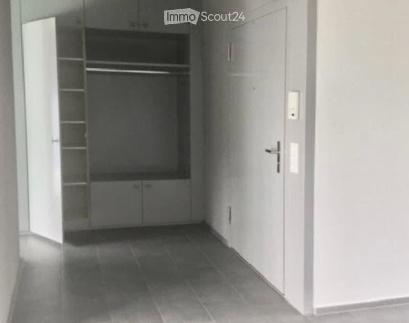 Empty hallway with tiled floor, white walls, and built-in closet with shelves and drawers.