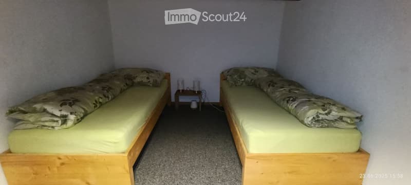 Two single beds with matching bedding, a small wooden nightstand with a lamp, and a carpeted floor.