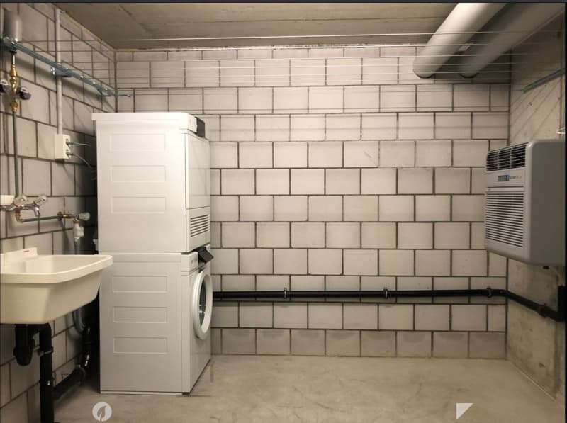 Utility room with a white tiled wall, a sink, a washing machine, and an air conditioner unit.