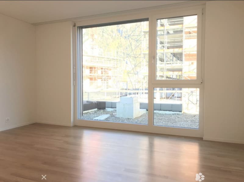 Empty room with wooden flooring, large windows, and white walls. No furniture or equipment present.