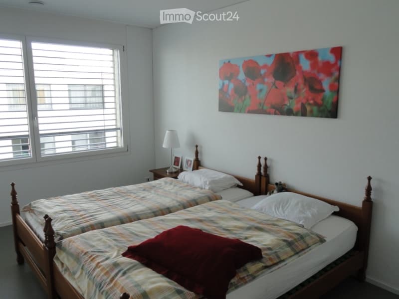 A twin-sized bedroom with two single beds, a nightstand, a lamp, and a colorful painting on the wall.