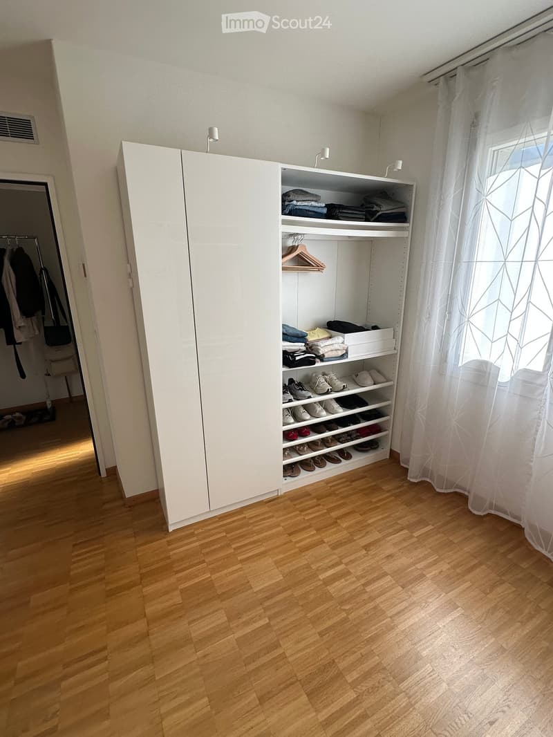 Empty room with wooden flooring, white built-in closet, and white curtain on the window. No furniture or personal items visible.