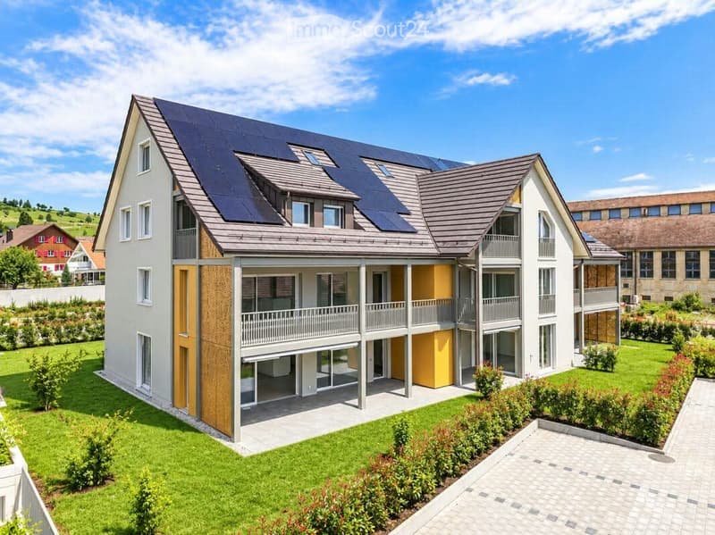 Modern two-story house with solar panels on the roof, white exterior, multiple windows, and a covered balcony area.