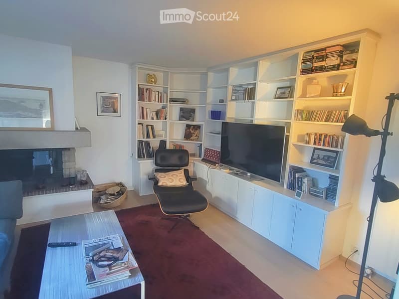 Modern living room with a fireplace, bookshelf, sofa, coffee table, and a comfortable chair.