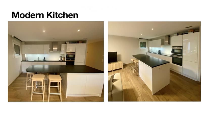 Modern kitchen with white cabinets, black countertops, and a central island with stools. Features include an oven, sink, and various kitchen appliances.