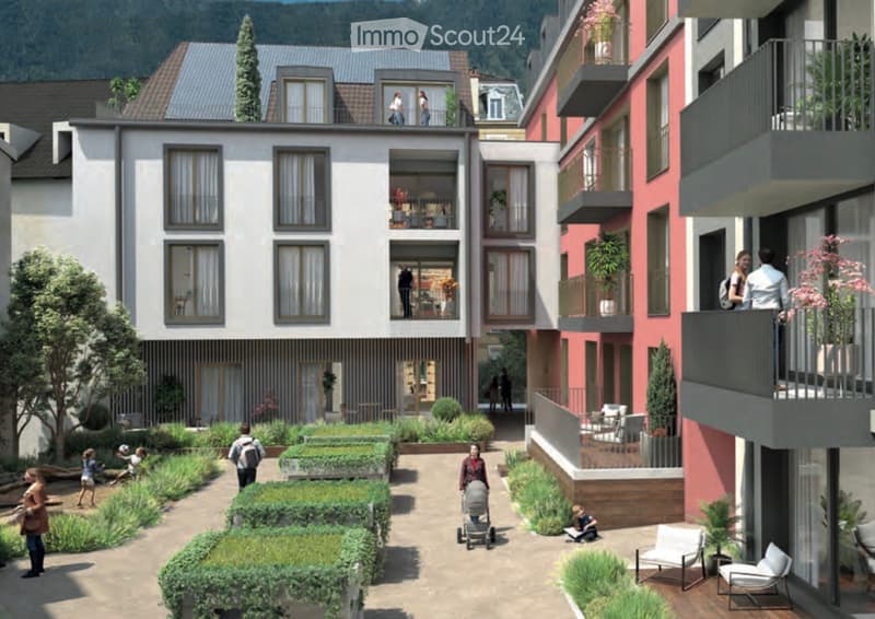 A modern residential complex with multiple apartment buildings, balconies, and a landscaped courtyard area with greenery and pathways.