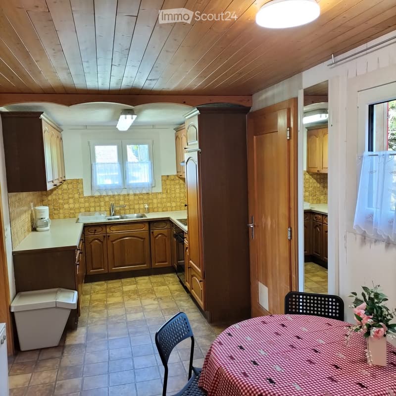 A cozy kitchen and dining area with wooden cabinets, a sink, refrigerator, and a dining table with chairs.