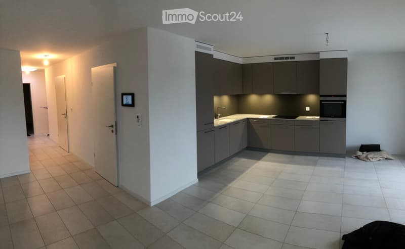 Modern kitchen with grey cabinets, white countertops, and built-in appliances including a microwave and oven. The space features tiled flooring and recessed lighting.