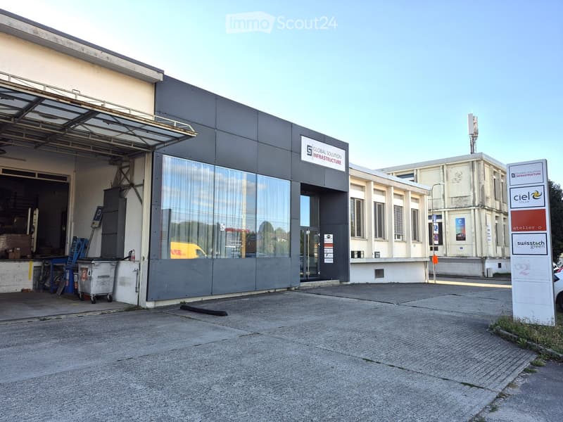 Modern industrial building with large garage entrance, signage for "Global Solution Infrastructure" and "Ciel Solar", and a paved parking area.