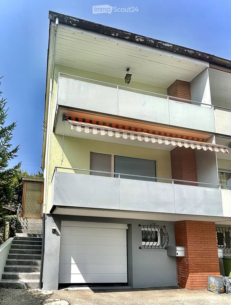 Two-story house with white and light green exterior, garage, balcony, and covered entrance with awning.