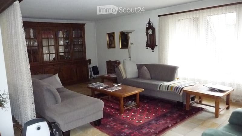 Living room with two sofas, coffee tables, a wooden cabinet, a clock on the wall, and a floor lamp.