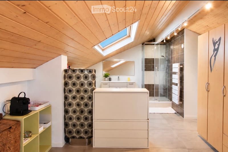 Modern bathroom with wooden ceiling, skylight windows, glass shower enclosure, white sink, and mirrored cabinet.