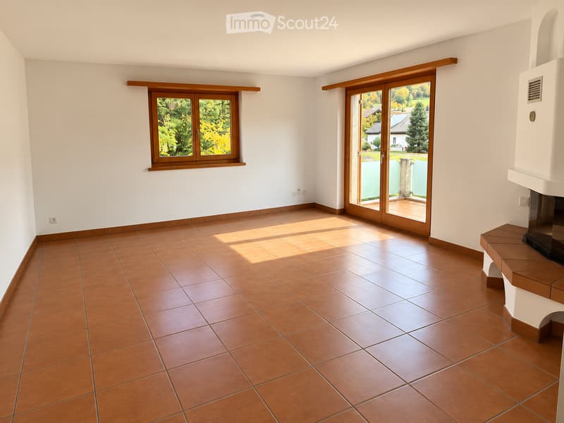 Empty room with brown tiled floor, white walls, large window, sliding glass door leading to outdoor area, and fireplace.