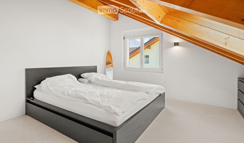 Bright bedroom with a double bed, white bedding, a mirror, and a window with a scenic view.