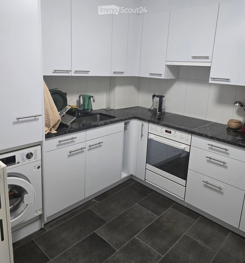 Modern kitchen with white cabinets, black granite countertops, stainless steel appliances, and a built-in oven.